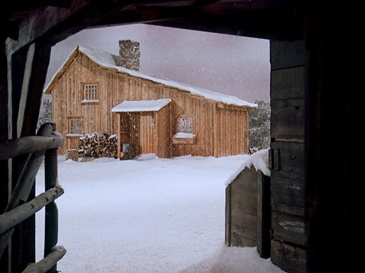 An indoors snowscape with the house seen from the barn